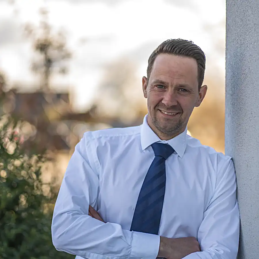 Profilbild Christian Knauer an Hauswand mit Hemd und Krawatte