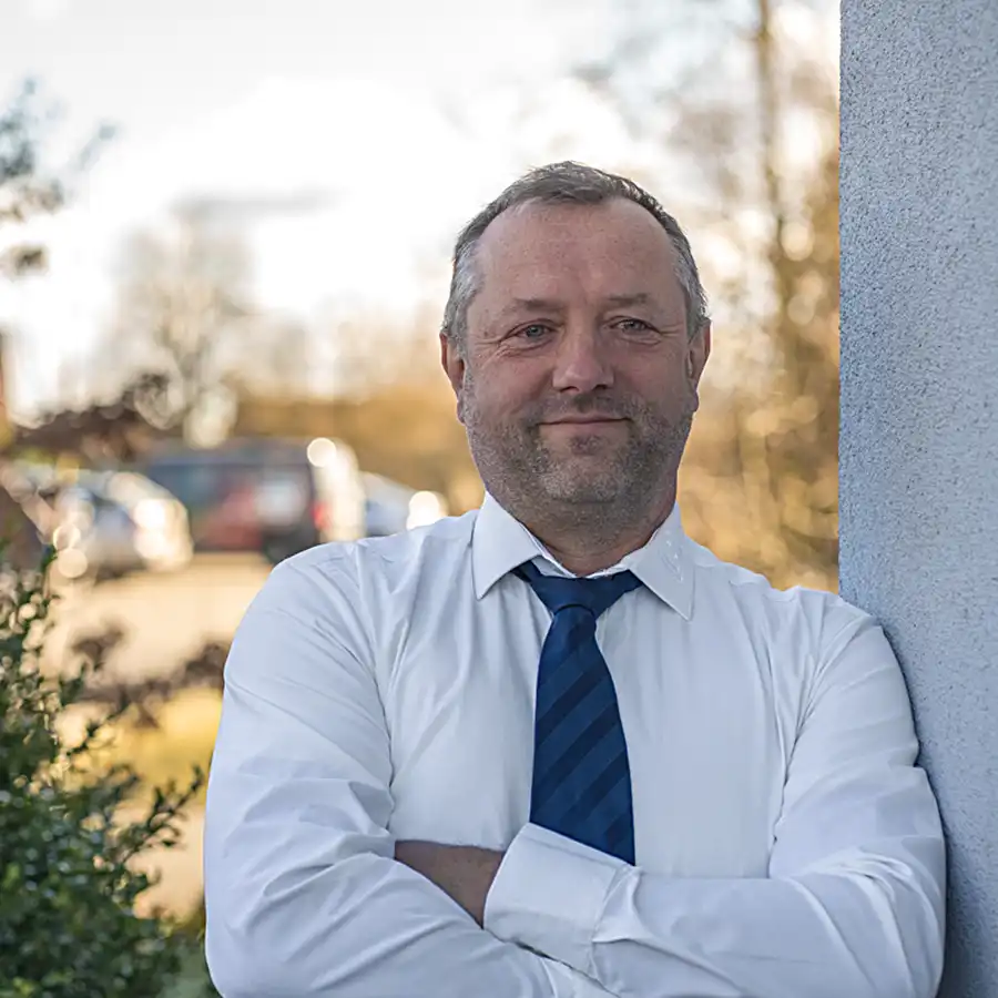 Profilbild Oliver Wolf an Hauswand mit Hemd und Krawatte