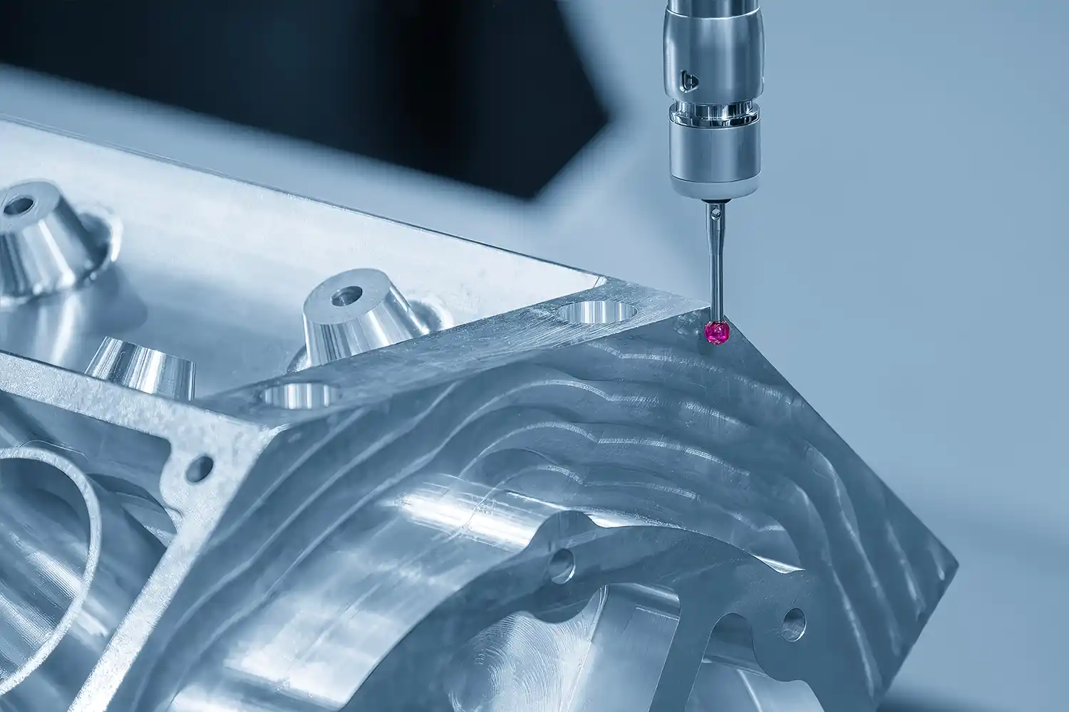 Die mehrachsige CMM-Maschine misst die Aluminium-Zylinderkopfteile in der hellblauen Umgebung.